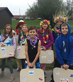 Students dressed up in hawaii clothes with pretend suitcases